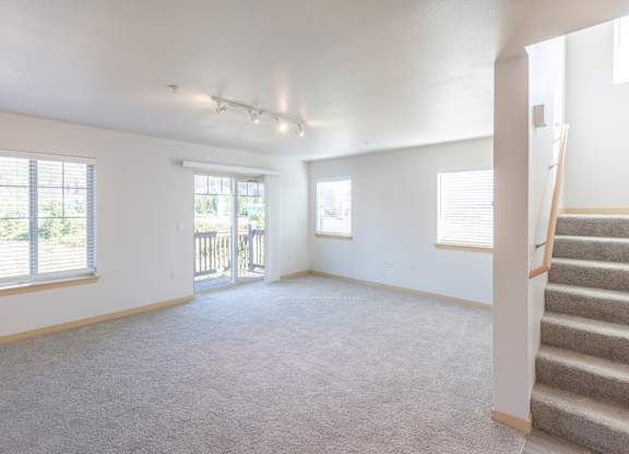 an empty living room with a staircase leading up to a balcony