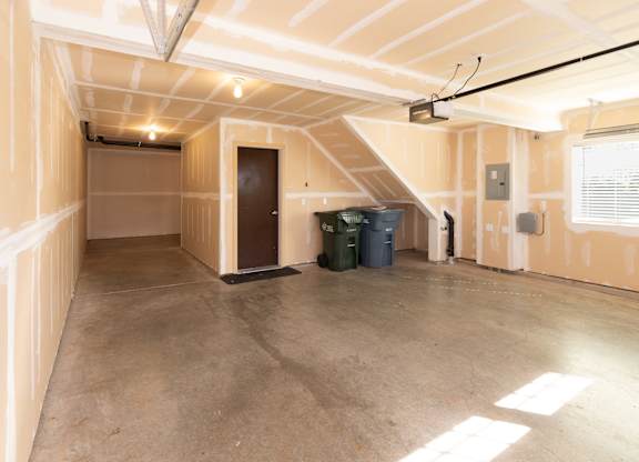 an empty garage with a door and two trash cans