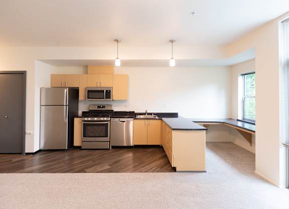 an empty kitchen with stainless steel appliances and wooden cabinets