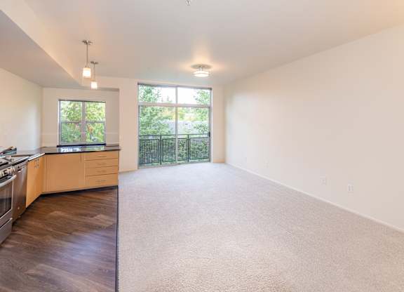 a spacious living room with a kitchen and a large window