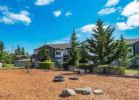 a yard with rocks and trees in front of a building