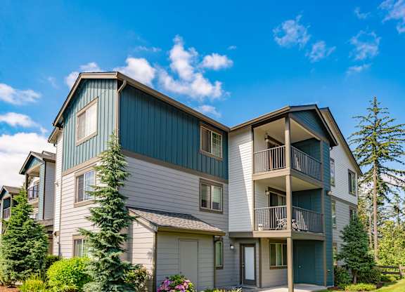 the view of two story apartment buildings with balconies and trees