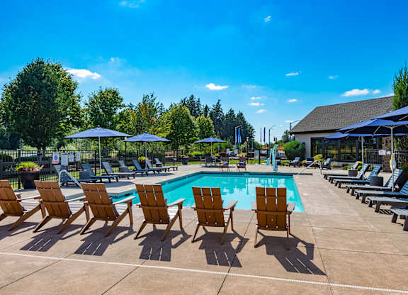 our resort style pool is filled with lounge chairs and umbrellas