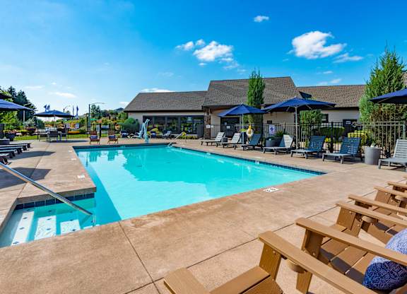 our resort style swimming pool is surrounded by lounge chairs and umbrellas