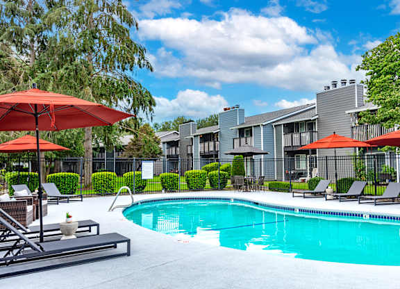a swimming pool with umbrellas in front of apartment buildings