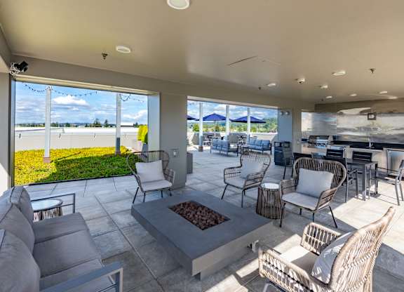 A patio with a fire pit and chairs.