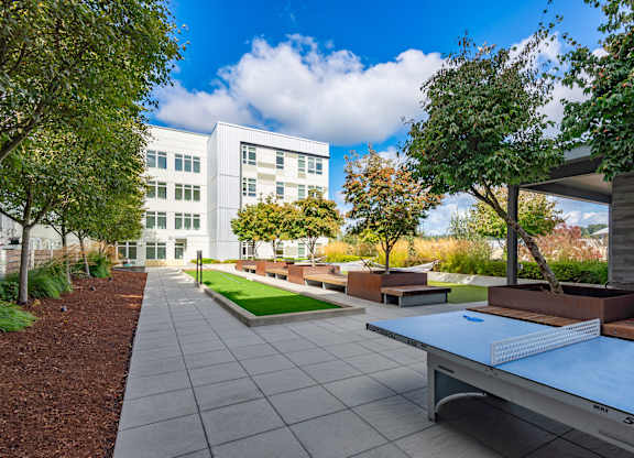 A ping pong table is in the middle of a courtyard.