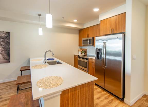 A kitchen with a white counter top and wooden cabinets.