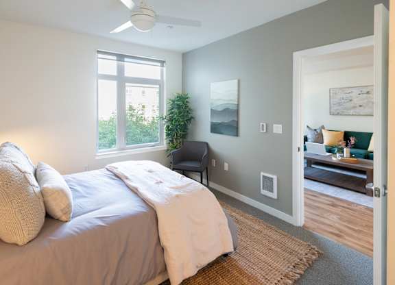 A bedroom with a bed, a chair, and a painting on the wall.