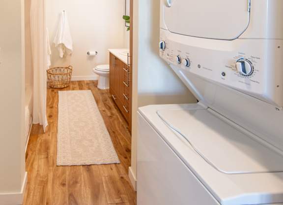 A white washing machine in a laundry room with wooden floors.
