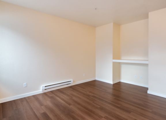 A room with wooden flooring and a wall-mounted air conditioner.