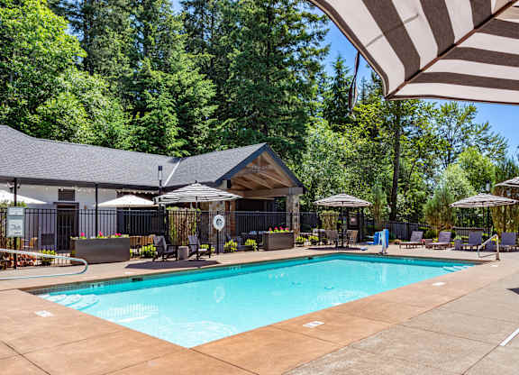 A large outdoor swimming pool surrounded by trees and a covered seating area.