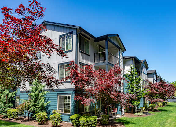 A row of houses with trees in front of them.