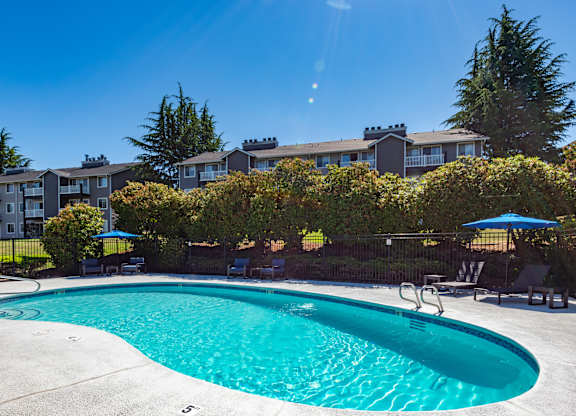 A swimming pool surrounded by a fence and trees.