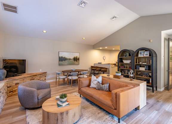 A living room with a brown couch, a grey armchair, a wooden coffee table and a bookshelf.