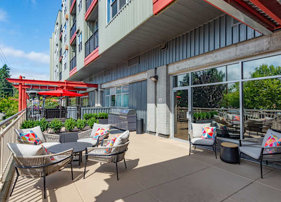 A patio with chairs and a table with a red umbrella.