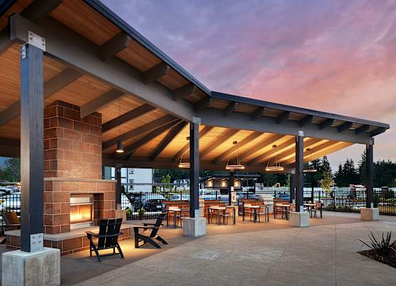 a patio with a fireplace and tables and chairs