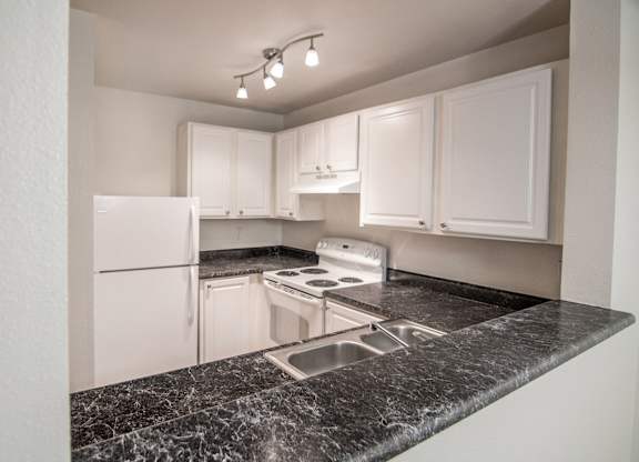 a kitchen with granite countertops and white appliances