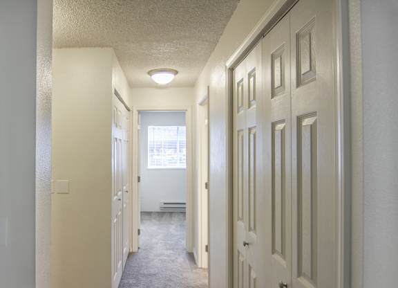 a hallway with white doors and a window