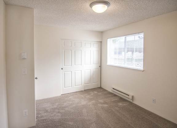 an empty bedroom with a window and a door