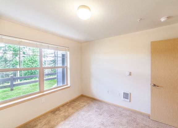 a bedroom with a large window and a wooden door