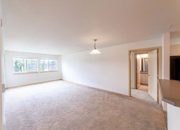 a spacious living room with white walls and carpet