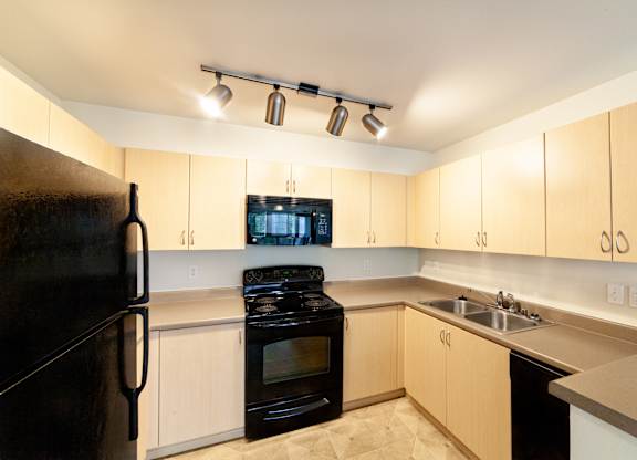 a kitchen with white cabinets and black appliances