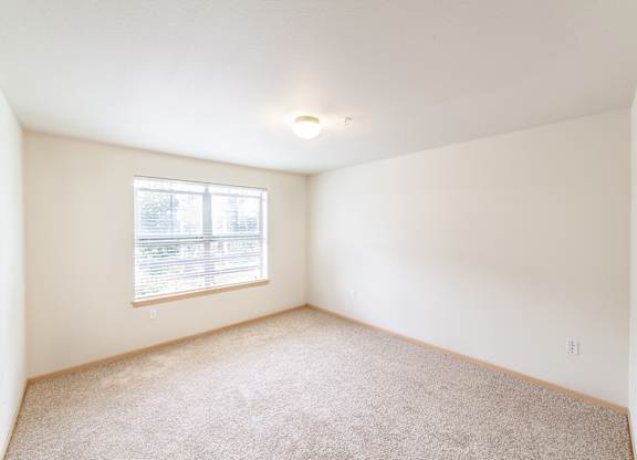 a bedroom with white walls and a window
