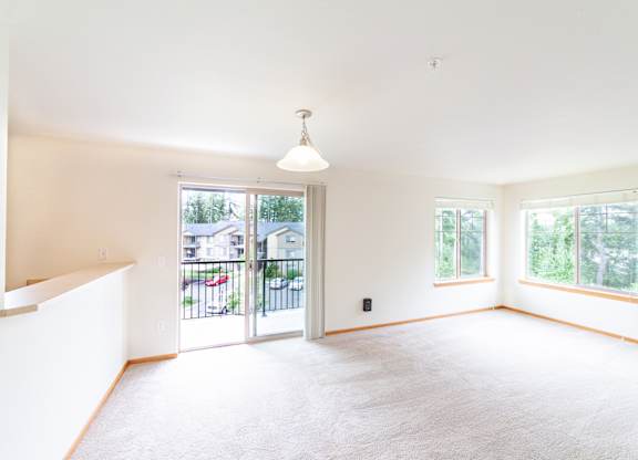 an empty living room with a sliding glass door and a balcony