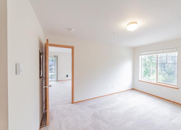 a bedroom with white walls and a large window