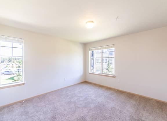 a bedroom with two windows and a carpeted floor