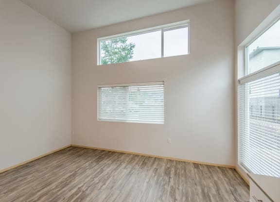 the spacious living room with large windows and wood flooring