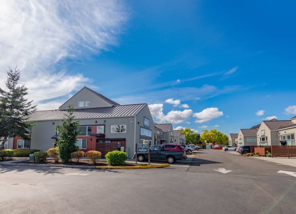 a parking lot in front of houses with a blue sky