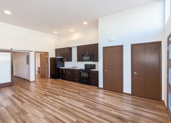 an empty living room with wood flooring and a kitchen