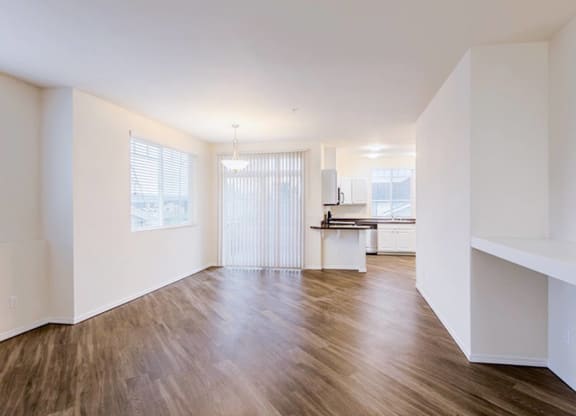 an empty living room with hard wood floors and a kitchen