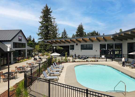 a swimming pool with lounge chairs and umbrellas in front of a building