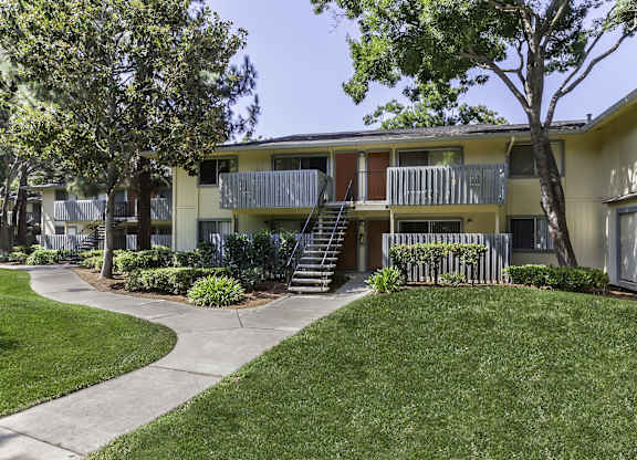 Apartment complex with a green lawn in front at The Woods Apartments, San Jose