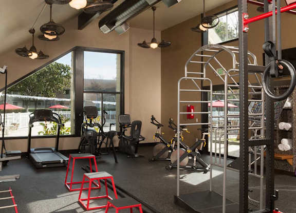 A gym with a variety of equipment including a treadmill, weights, and a pull up bar at The Woods Apartments, California, 95136