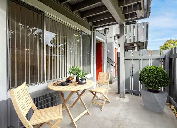 A small table with two chairs is on a patio at Cherrywood Apartments, San Jose, CA, 95118