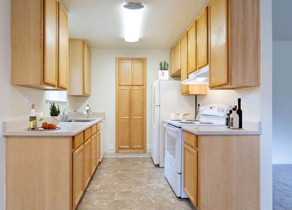 A kitchen with wooden cabinets and a white refrigerator at Cherrywood Apartments, San Jose, 95118