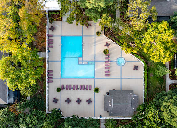 An aerial view of a pool surrounded by trees and a building at Cherrywood Apartments, San Jose, California