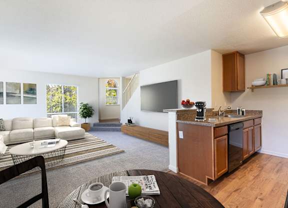 A modern living room with a white sofa and a wooden kitchen area at The Woods Apartments, California