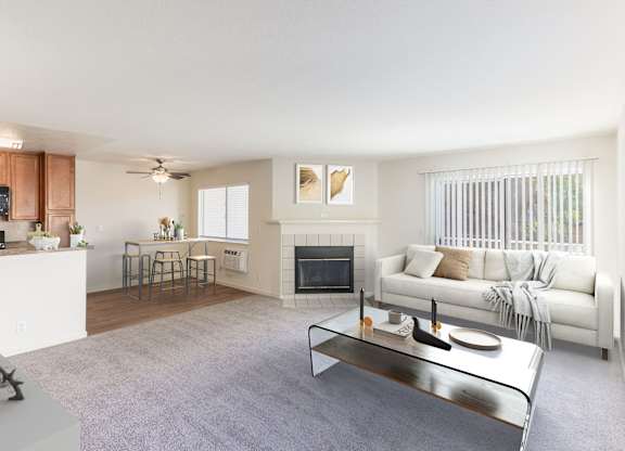 A modern living room with a fireplace and a glass coffee table at The Woods Apartments, San Jose, California