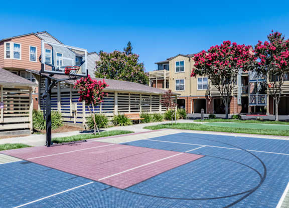 A basketball court in front of apartment buildings.