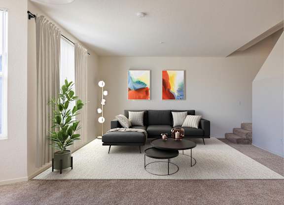 A living room with a black couch, a small table, and a painting on the wall at The Woods Apartments, San Jose, California