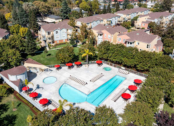 An aerial view of a pool surrounded by trees and buildings.