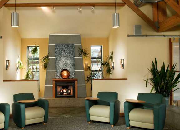 A living room with a fireplace and four chairs at The Woods Apartments, San Jose