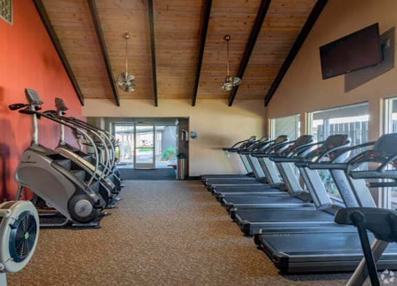 A gym with treadmills and elliptical machines at Cherrywood Apartments, San Jose