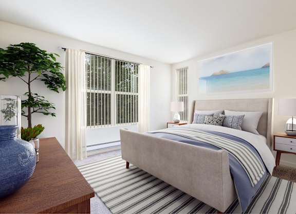 A bedroom with a large bed and a painting of a beach scene on the wall at The Woods Apartments, San Jose