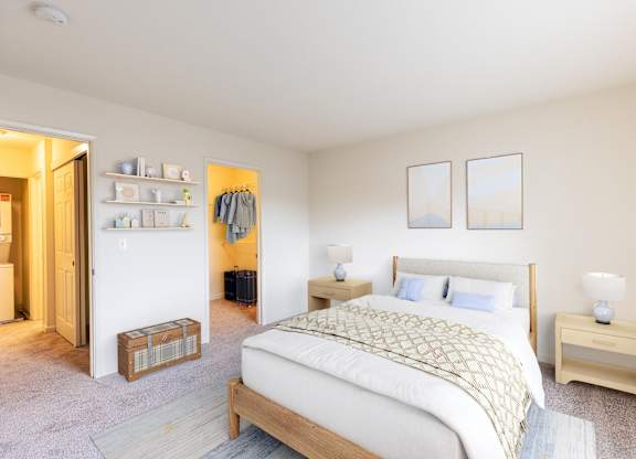 A bedroom with a bed, nightstand, and a closet with clothes hanging at The Woods Apartments, San Jose, 95136